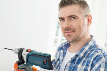 Portrait of mid-adult man drilling hole in wall