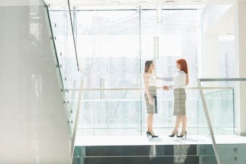Fototapeta na wymiar Full-length of businesswomen shaking hands in office