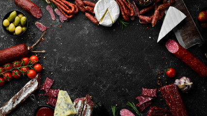 Assortment of cheese, salami, sausage, spices and meat products, on black background. Top view....