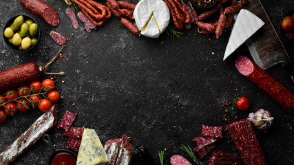 Assortment of cheese, salami, sausage, spices and meat products, on black background. Top view....