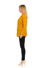 Standing Young Woman In Yellow Jacket And High Heels. Side View.