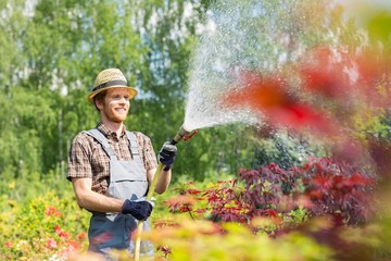 Smiling man watering plants at garden