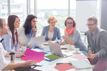 Creative business colleagues analyzing photographs at conference table in office