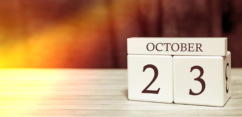 Calendar reminder event concept. Wooden cubes with numbers and month on October 23 with sunlight.