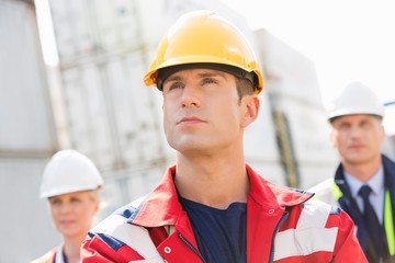 Confident male worker with colleague in background at shipping yard