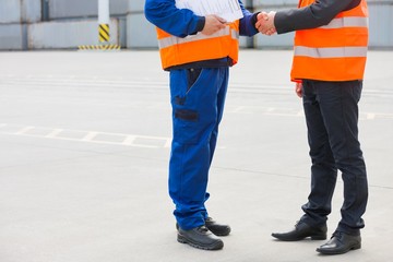 Low section of workers shaking hands in shipping yard