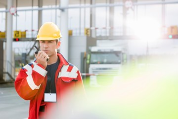 Mid adult worker using walkie-talkie in shipping yard
