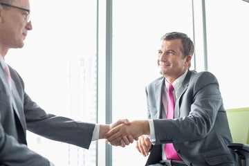 Mature businessmen shaking hands in office