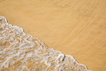 Fototapeta na wymiar Water waves crushing on a sandy beach - sand summer sun swim swimming wave yellow wet crush rolling splash splashing holiday vacation