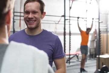 Happy man talking to male friend in crossfit gym