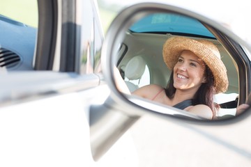 Reflection of happy woman in rearview mirror of car