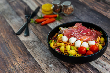 Salad made with cooked pasta, mixed green salads, cherry tomatoes, Mozzarella cheese and smoked ham served with accompaniment