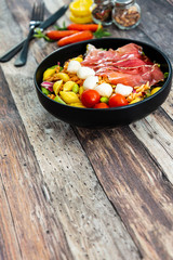 Salad made with cooked pasta, mixed green salads, cherry tomatoes, Mozzarella cheese and smoked ham served with accompaniment