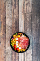 Salad made with cooked pasta, mixed green salads, cherry tomatoes, Mozzarella cheese and smoked ham served with accompaniment