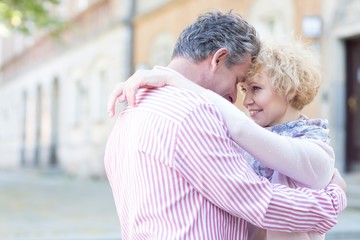 Happy middle-aged couple embracing in city