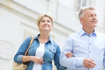 Smiling middle-aged couple standing with arm in arm outdoors