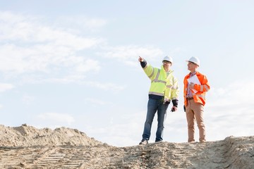 Low angle view of supervisor showing something to colleague at construction site