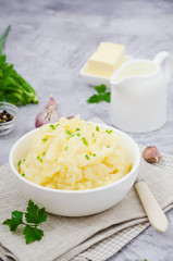 Obraz na płótnie Canvas Mashed potatoes with butter, milk, garlic and green onions in a bowl on a gray background. A traditional dish of Ukrainian, Russian cuisine. Vertical orientation. Close up.