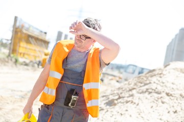 Tired construction worker wiping forehead at site