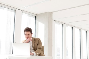 Young businessman using laptop at desk in new office