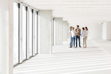 Full length of business people discussing in empty office