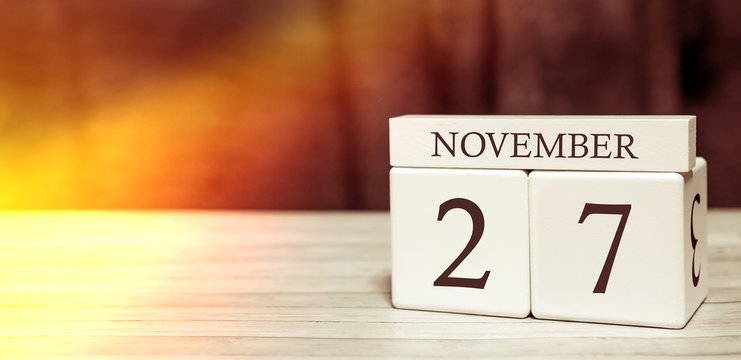 Calendar reminder event concept. Wooden cubes with numbers and month on November 27 with sunlight.