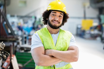 Portrait of smiling male manual worker standing arms crossed in industry