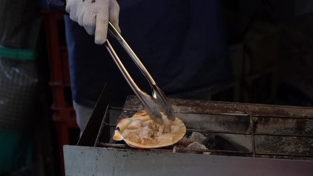 Slow motion of Japanese chef is grilling Fresh Scallops - Hotate Meat, a famous street food in Japan.