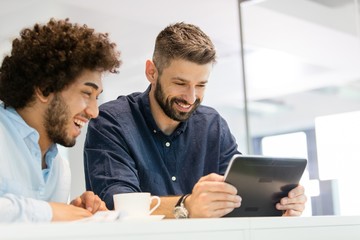 Smiling businessmen using digital tablet in office