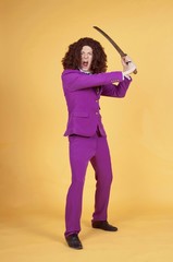 Angry young man in purple suit wearing wig while holding samurai