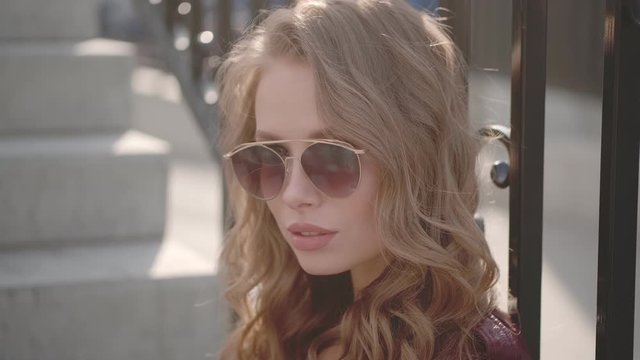 Attractive girl playfully looks at the camera over sunglasses