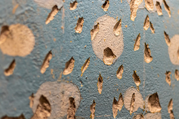 Tiled wall. Preparation for repair. Broken and gritty surface. Rough texture of blue color with brown spots.