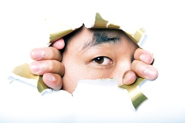 Young Korean man looking through ripped paper hole