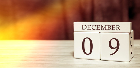 Calendar reminder event concept. Wooden cubes with numbers and month on December 9 with sunlight.