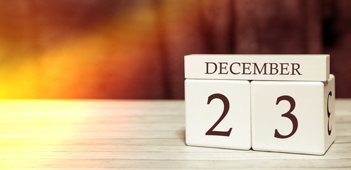 Calendar reminder event concept. Wooden cubes with numbers and month on December 23 with sunlight.