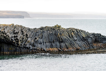 Closeup shot of rocky basalt volcanic textured columns in Kalfshamarsvik in Iceland during heavy...