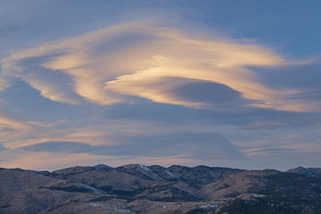 Winter landscape at sunset of lenticular clouds and of the Front Range of the Rocky Mountains from...