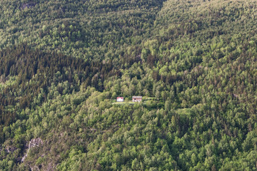 Luftbild: Einsames Haus mit Scheune inmitten der gewaltigen Weiten der norwegischen Natur, in einem Wald an einem Fjordhang an der Westküste 