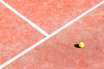 High angle view of tennis ball on red court during sunny day