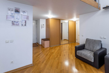 Entrance hall in private house. Grey chair. Wardrobe with mirror.