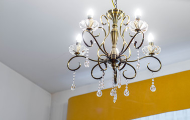 Hanging chandelier with lights on. White walls and ceiling.