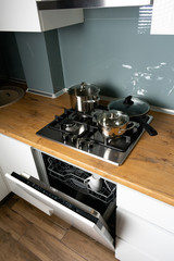 Modern stainless steel gas stove oven in a home with various cookware