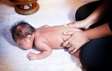 Obraz na płótnie Canvas The newborn baby was massaging by Therapist hands,for stimulate development program,blurry light around