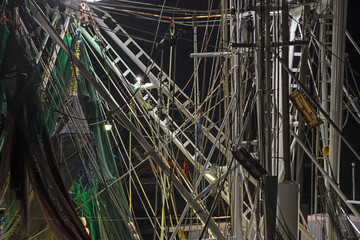 Obraz premium nighttime detail of the ropes, pulleys, ladders, nets and rigging of a commercial shrimp boat.