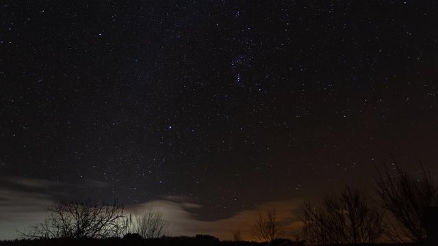 Space time lapse of Orion constellation, movement of Milky way with clouds, light pollution area in 4K