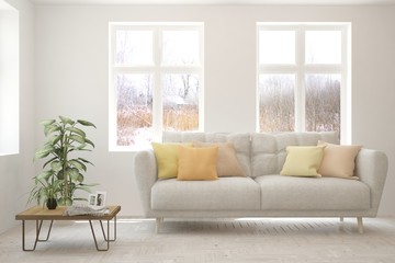 Fototapeta premium Stylish room in white color with sofa and winter landscape in window. Scandinavian interior design. 3D illustration