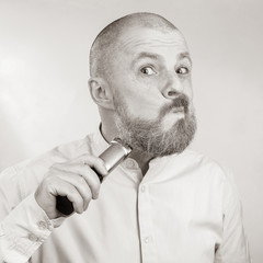 bearded man in a light coloured shirt makes the correction beard trimmer