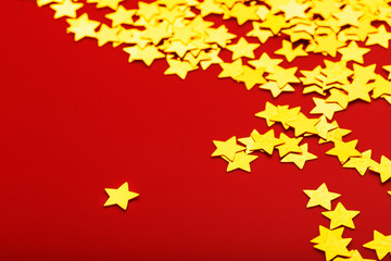 Gold stars on red background. The concept of greeting cards, headlines and web site. A scattering of Golden stars