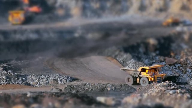 Coal mining in quarry, tilt-shift panorama yellow dump truck carries coal