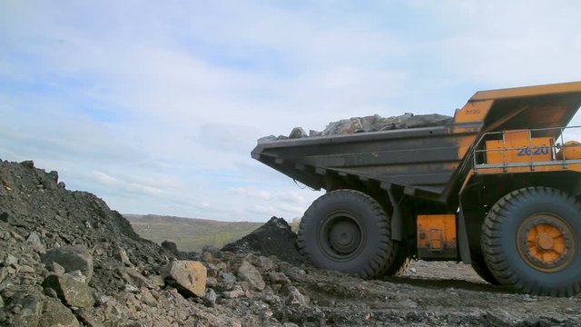 Huge yellow tipper truck rides backwards and stops, it is going to unload the earth and stones